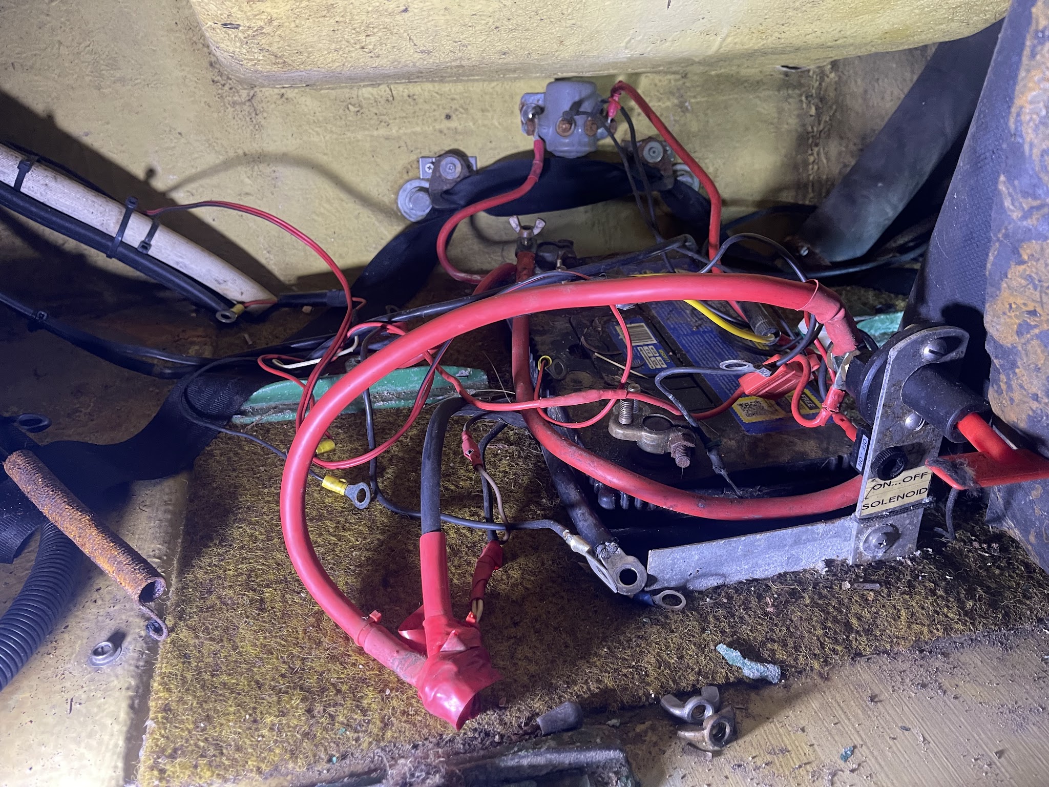 Battery, isolator and heavy gauge cable inside a boat hull before rewiring