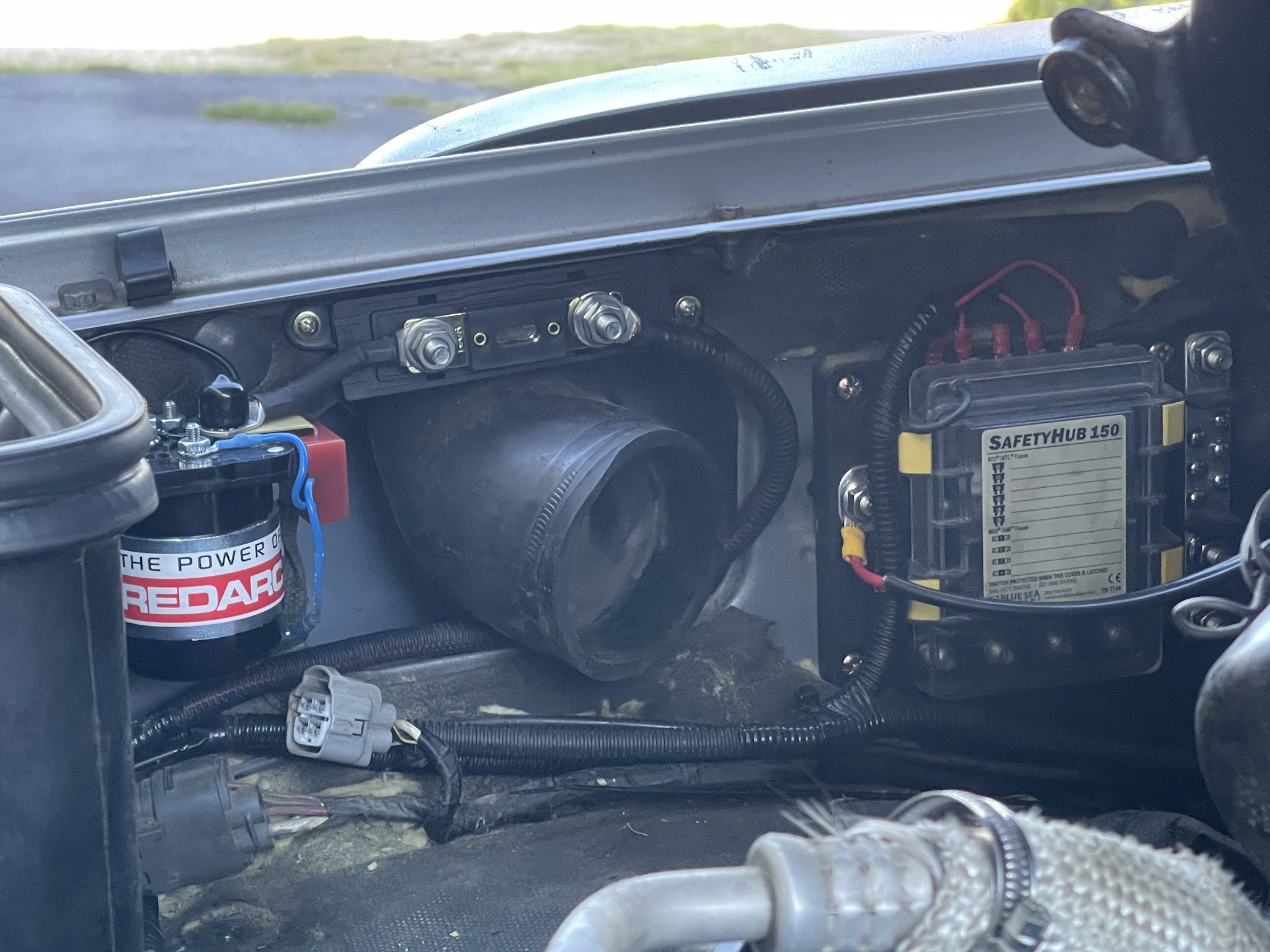 A solenoid and a marine grade fuse block freshly mounted in an engine bay as part of a dual battery install